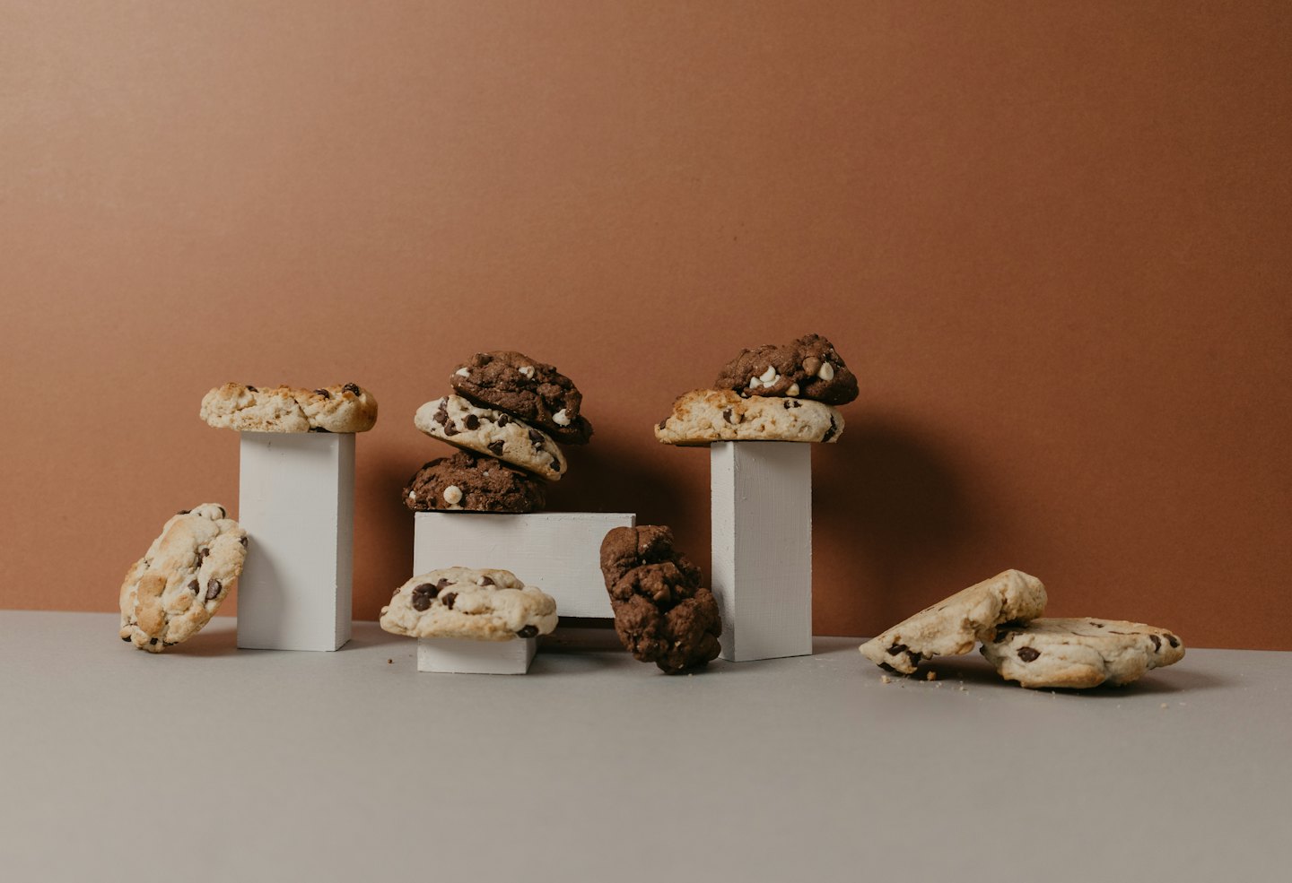 Assorted chocolate chip cookies arranged on stacked white pedestals.