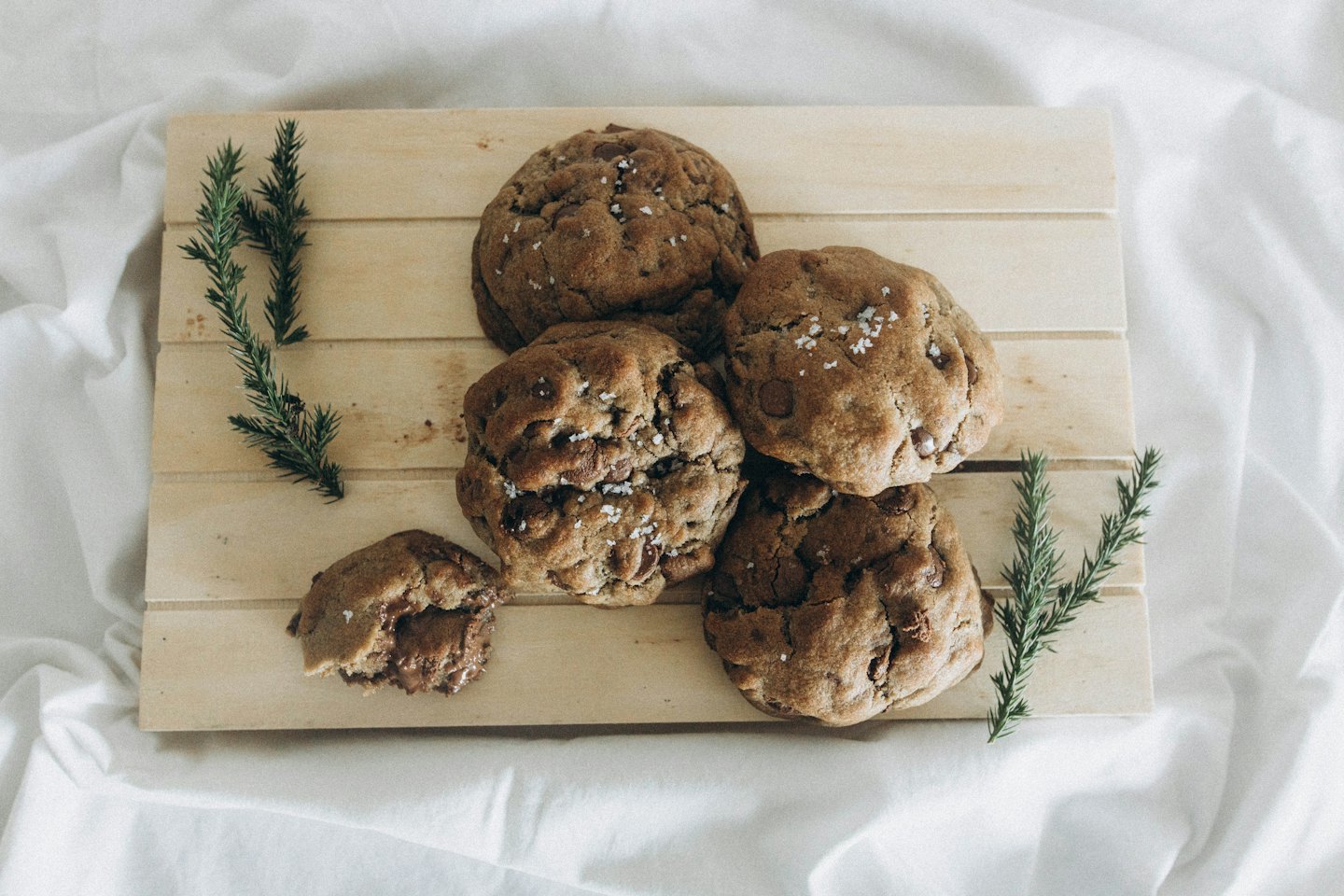 Homemade chocolate chip cookies with sea salt on a wooden board.